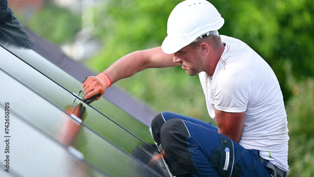 Worker building photovoltaic solar panel system on rooftop of house. Man engineer in helmets and gloves installing solar module with help of hex key outdoors. Alternative energy generation concept. Worker building photovoltaic solar panel system on rooftop of house. Man engineer in helmets and gloves installing solar module with help of hex key outdoors. Alternative energy generation concept.