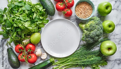 fresh raw greens unprocessed vegetables and grains over light grey marble kitchen countertop wtite plate in center top view copy space healthy clean eating vegan detox dieting food concept