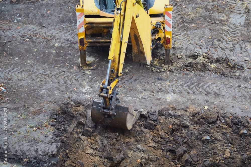 Yellow excavator doing earthworks, excavator bucket digging soil, excavator on a construction site Yellow excavator doing earthworks, excavator bucket digging soil, excavator on a construction site
