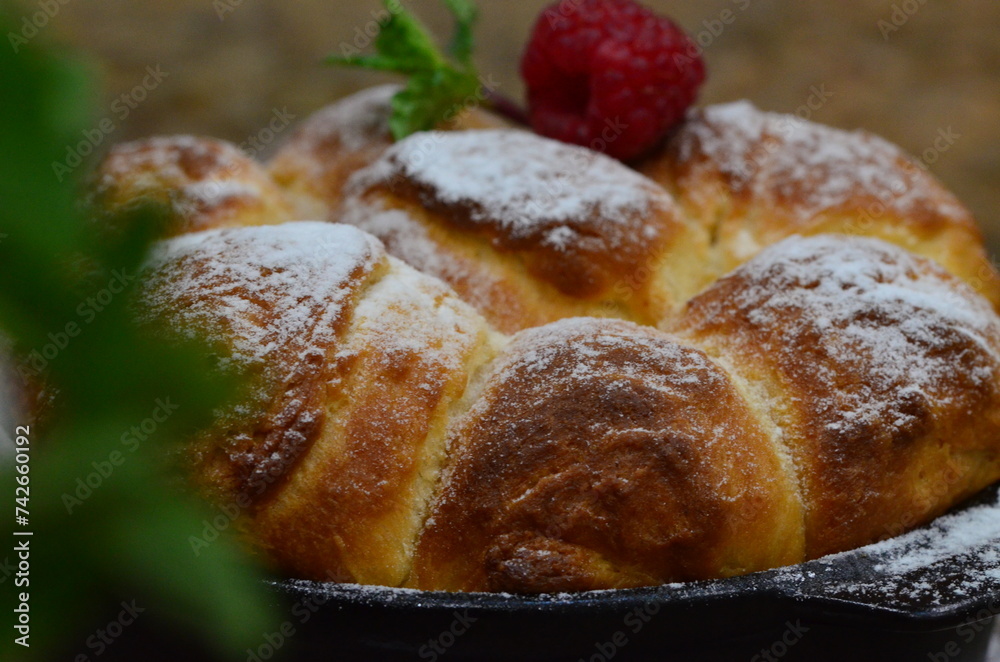 Freshly baked buns with raspberries and powdered sugar.