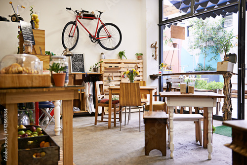 Interior, bike on wall of empty coffee shop with tables and chairs for retail, service or hospitality. Space, small business or startup restaurant with cafeteria seating for bistro consumerism photo