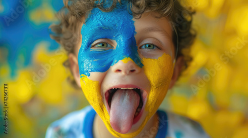 child boy on the face yellow and blue paint shows the tongue, national colors of the flag of Ukraine photo