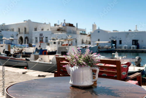 Flower arrangement in teapot on table with the harbour in the background  in Paros, Greece © Lucia Tieko