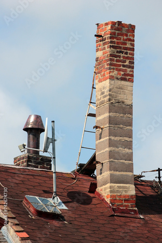 фотографія Old brick smokestack on a rooftop with a metal ladder for servicing