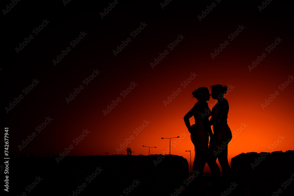 contraluz de dos mujeres jovenes mirandose frente a frente en un fondo de la ciudad 