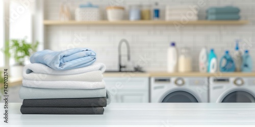 stack of fold clothes on white table with blur laundry room background copy space © kimly