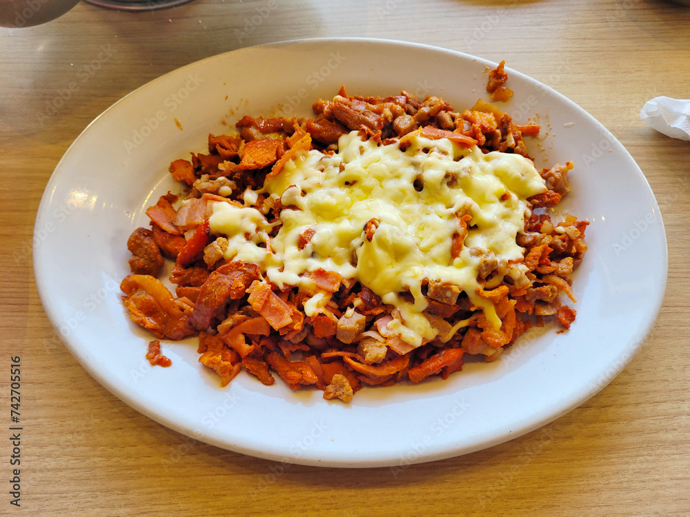 Plate of Spicy Al Pastor topped with cheese, served with fresh salsa and onions Plate of Spicy Al Pastor topped with cheese, served with fresh salsa and onions
