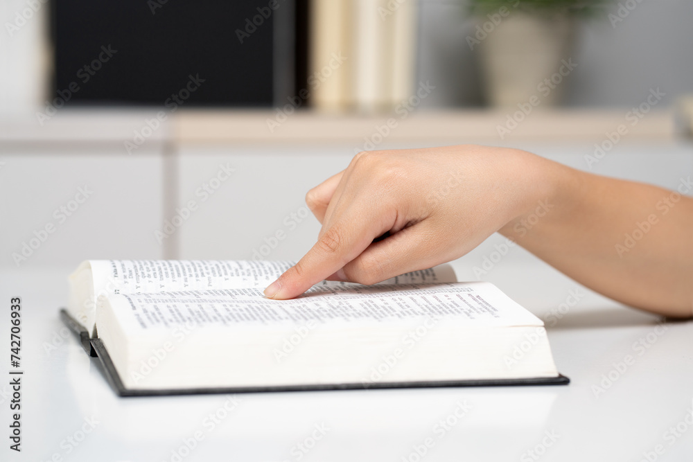 Close up christian child reads Holy Bible at home. Male hands open book of holy scripture in cozy room