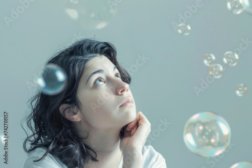Thinking woman with many ideas in empty bubble on grey background looking up.