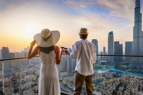 Photography A elegant couple stands on a balcony and enjoys the sunset behind the skyline of