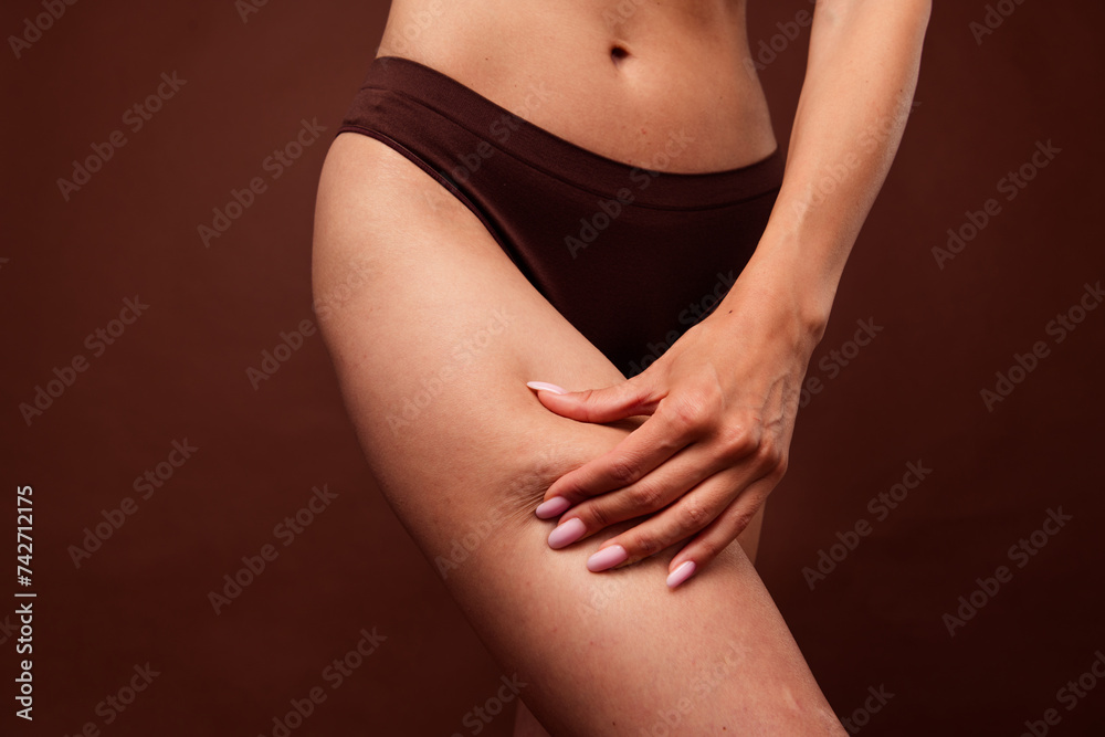 No retouch cropped photo of natural thin woman wear lingerie hand showing cellulite on hips isolated on dark brown color background