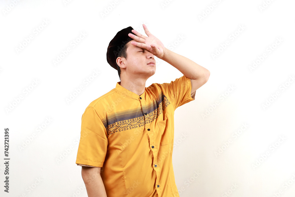 Unhealthy Asian Muslim man suffering from headache isolated on white background Unhealthy Asian Muslim man suffering from headache isolated on white background