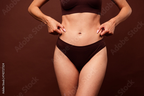 Cropped photo no retouch of lovely young lady clamp belly stomach folds wear trendy lingerie isolated on brown color background