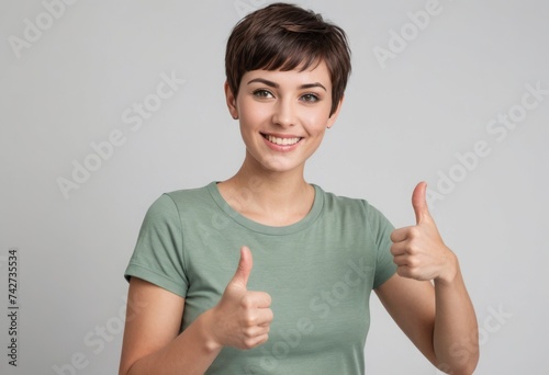 A happy woman in a green t-shirt gives a double thumbs up, her short haircut and bright smile radiating friendliness and enthusiasm.