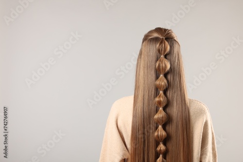Woman with braided hair on grey background, back view. Space for text