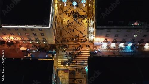 Aerial drone shot of European city street with Christmas and New Year decorations for holiday season. Above shot of Lisbon decorated street amidst buildings. 