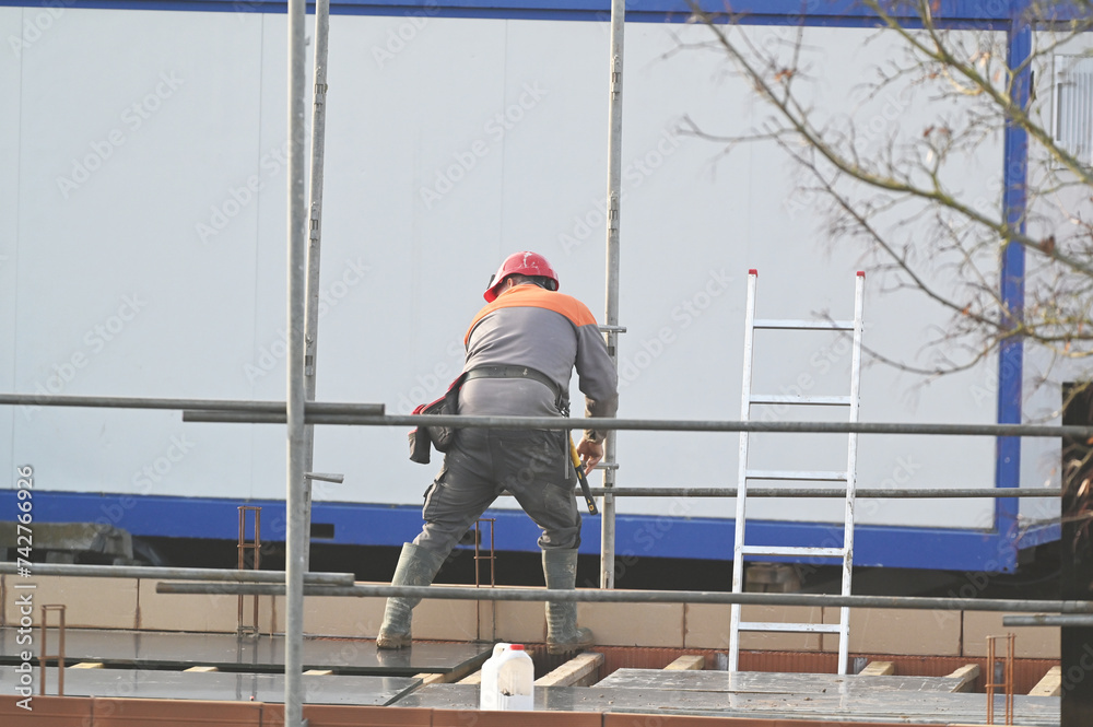 ouvrier montant un échaffaudage sur un chantier de construction