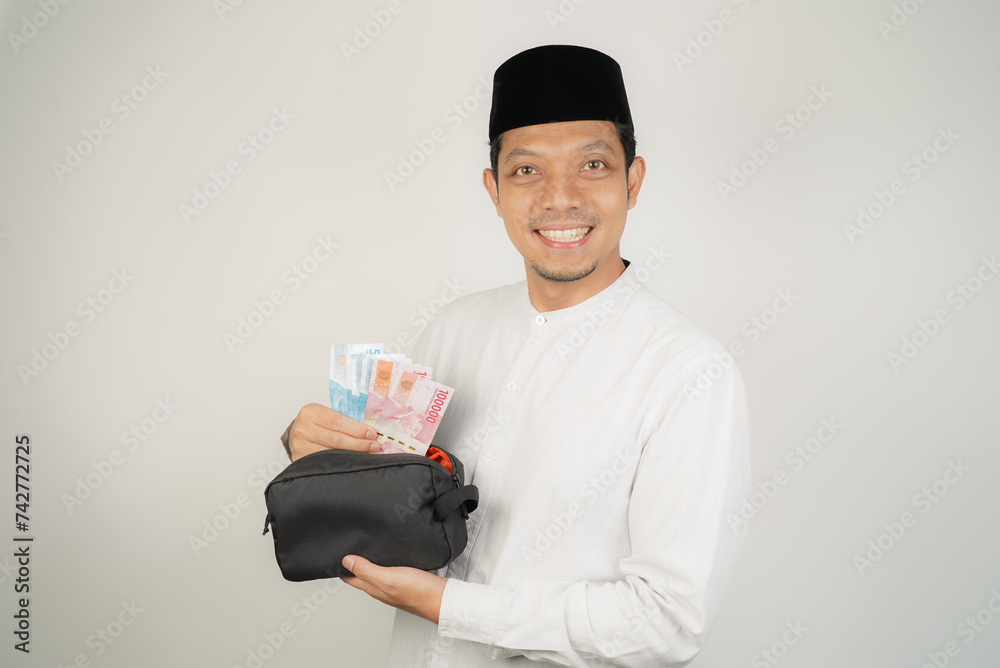 happy asian muslim man holding money, wearing arabic costume on isolated background happy asian muslim man holding money, wearing arabic costume on isolated background