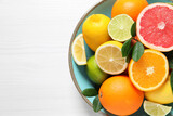 Different cut and whole citrus fruits on white wooden table, top view. Space for text