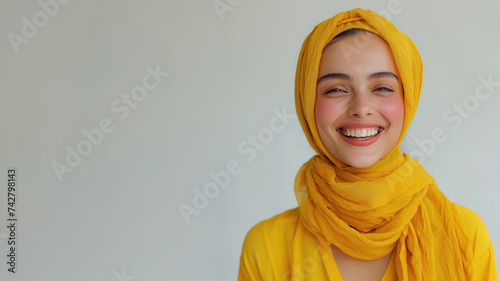 Arab woman wearing yellow shirt smiling laugh out loud isolated on grey © pariketan