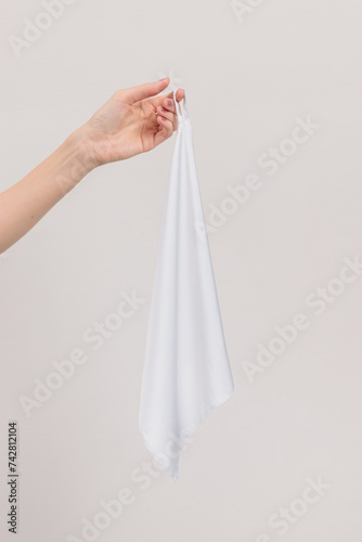 a woman s hand holds a piece of white silk fabric  towel    her palm facing us  with one finger