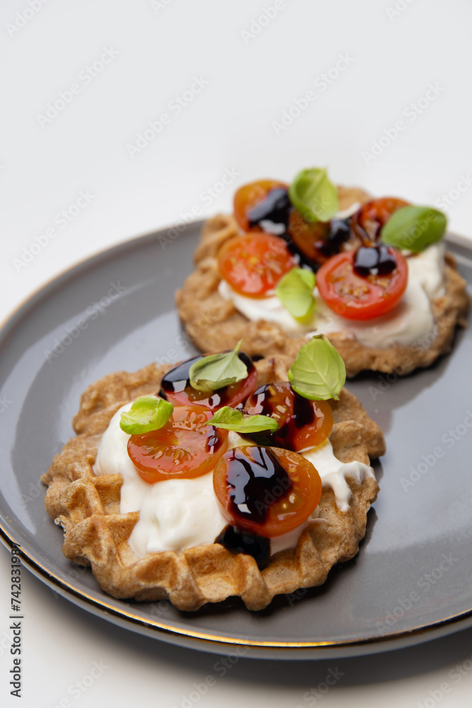 Homemade Belgian cauliflower waffles. waffles are decorated with natural yogurt, cherry tomatoes, basil leaf, presented on a plate for a healthy breakfast.	  