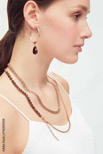 Close up portrait of a beautiful elegant woman with freckles with stylish jewelry on a white background. Beautiful girl with jewelry.