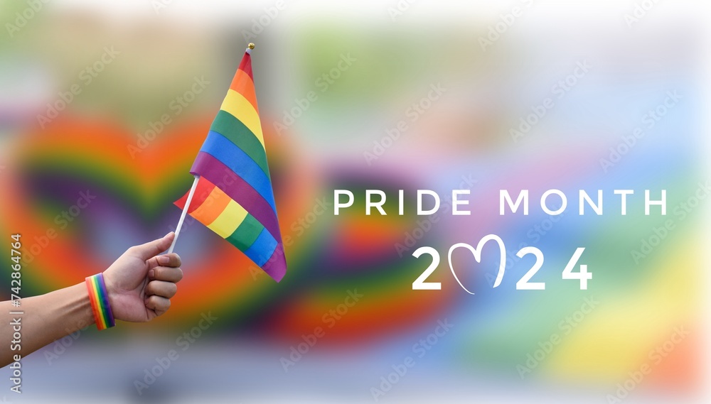Pride Month 2024 and rainbow flag raising on blurred rainbow flags and wristband background, concept for celebration of LGBT people around the world in pride month. Pride Month 2024 and rainbow flag raising on blurred rainbow flags and wristband background, concept for celebration of LGBT people around the world in pride month.