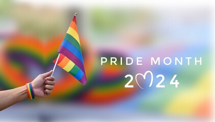Pride Month 2024 and rainbow flag raising on blurred rainbow flags and wristband background, concept for celebration of LGBT people around the world in pride month.