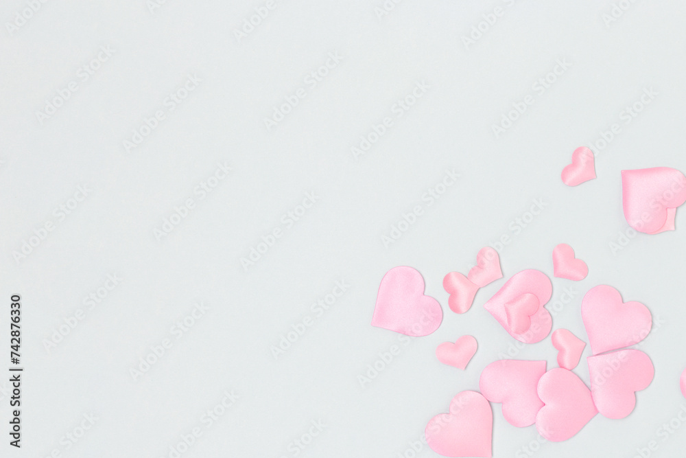 Pink textile hearts confetti scattered on a blue background. Place for your design.