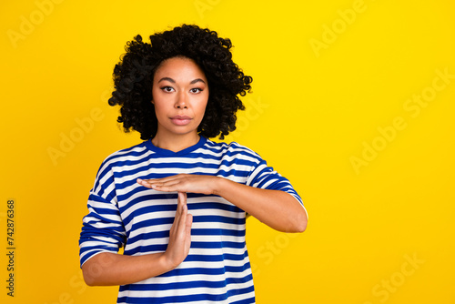 Photo of confident serious girl wear stylish clothes showing gesture stop time symbol empty space isolated on yellow color background © deagreez