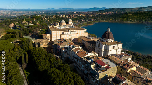 Aerial view of the Papal Palace of Castel Gandolfo. The Apostolic Palace is a complex of buildings served for centuries as a summer residence for the Pope. In background the city of Rome, Italy.  photo