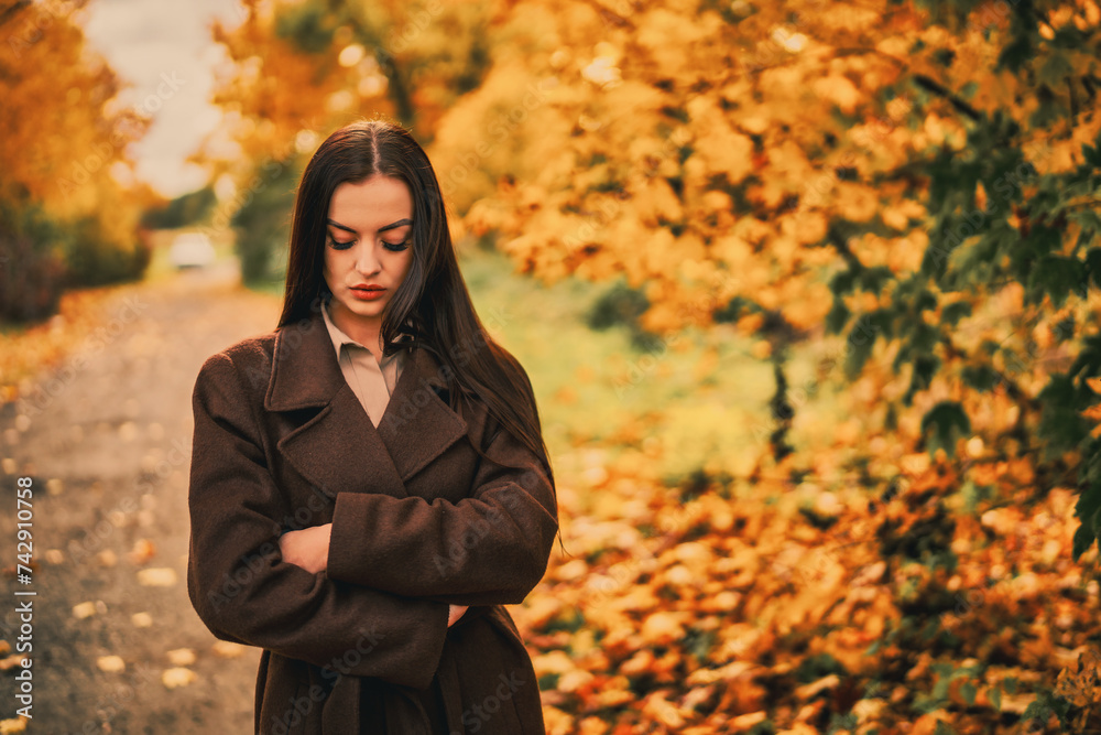Φωτογραφία Portrait of a young woman in a brown coat in autumn