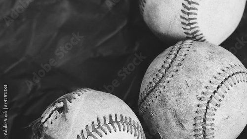 Dark old used vintage baseball balls in rugged black and white texture with copy space on background for sports or athletics team concept.