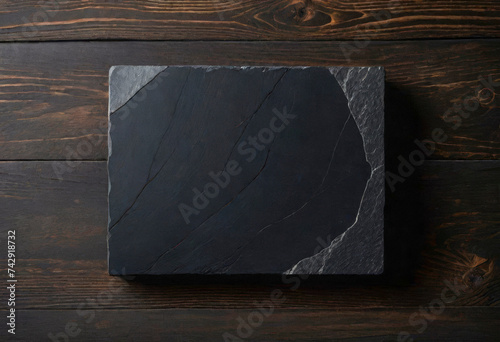 black stone slab plaque on wooden surface, simple background, minimalist