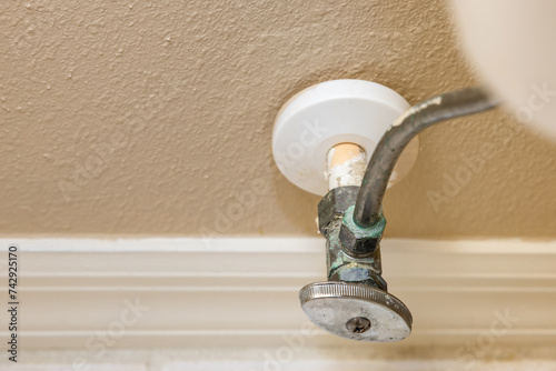Residential home bathroom toilet water shut off valve. Replacing old leaking restroom wall supply line valve plumbing.
