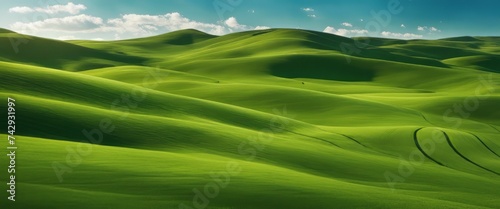 Idyllic Rolling Green Hills Under a Clear Blue Sky with Wispy Clouds. Tranquil Nature Landscape © Adi
