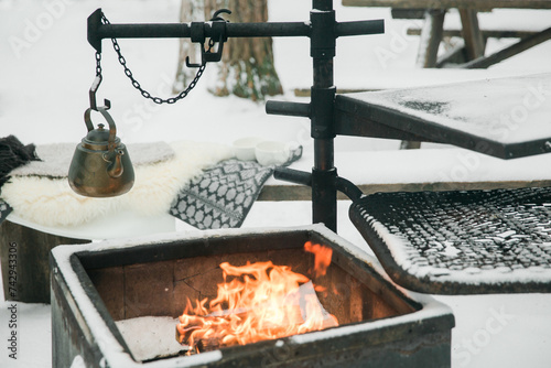 Outdoor winter picnic with hot coals and teapot on fire photo