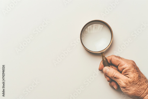 Man's hand, holding classic styled magnifying glass, closeup on white background. Space for text.