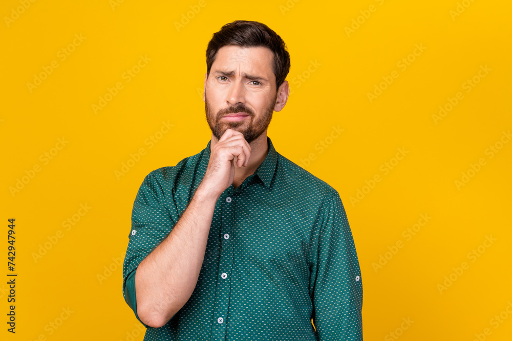 Portrait of dissatisfied gloomy man with beard wear stylish shirt hold hand on chin thinking isolated on vivid yellow color background Portrait of dissatisfied gloomy man with beard wear stylish shirt hold hand on chin thinking isolated on vivid yellow color background