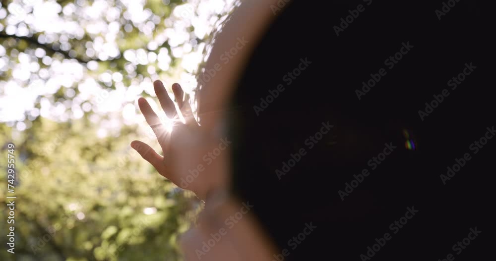 Closeup view of female hand isolated on sunny sunset golden sky and meadow background. Woman enjoying soft evening sun light outside. Sunrays sparkling between among fingers of person. Closeup view of female hand isolated on sunny sunset golden sky and meadow background. Woman enjoying soft evening sun light outside. Sunrays sparkling between among fingers of person.