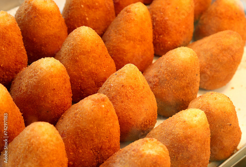 fried food called arancini ora ARANCINE in italian language filled with rice vegetables meat or cheese on sale at a market stall in Sicily southern Italy