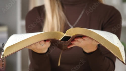 A woman's hand holds a book. A mysterious book opening. Story of the book. Selective focus on paperback. Female holding bible in hands. Opening of Holy Bible, closeup