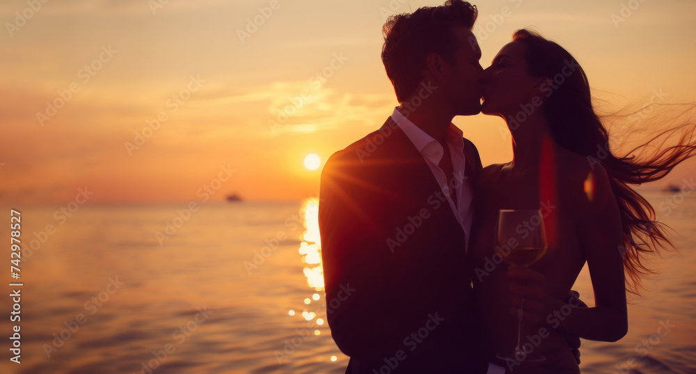 Man and woman share romantic kiss on quiet beach. Young male and female embrace standing together on beach against picturesque sunset.