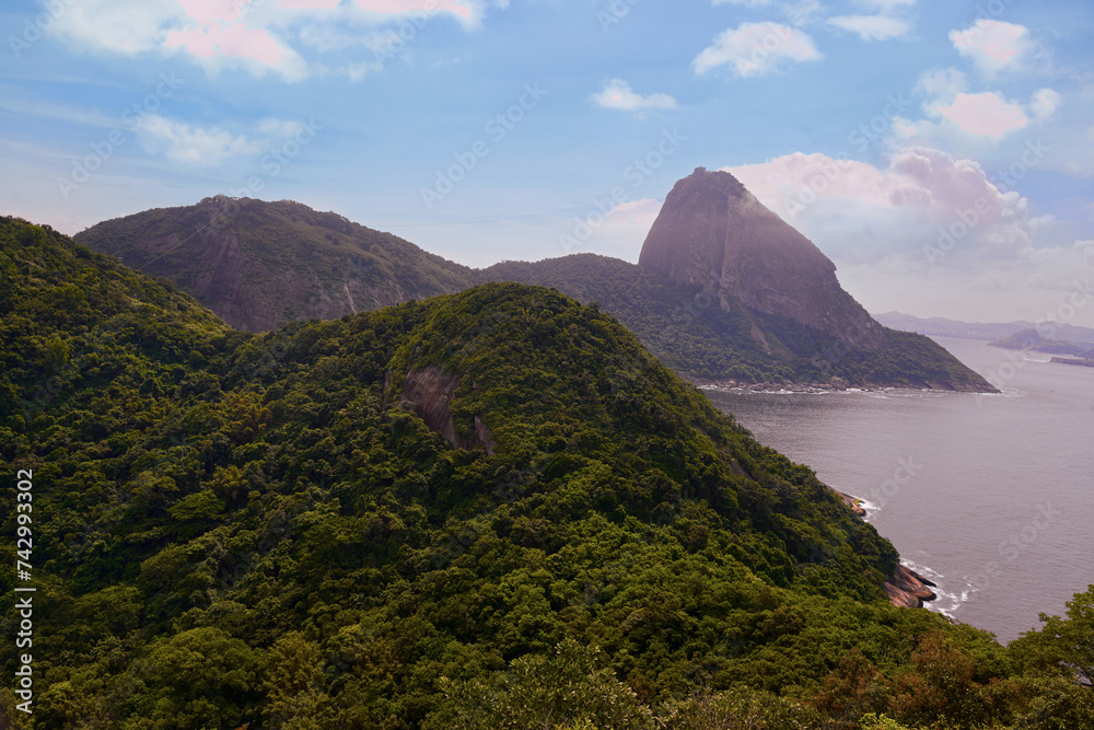 Sugar Loaf Mountain seen from the Leme neighborhood of Rio de Janeiro. Lush vegetation of the Atlantic Forest, blue sky and sea make up the scene Sugar Loaf Mountain seen from the Leme neighborhood of Rio de Janeiro. Lush vegetation of the Atlantic Forest, blue sky and sea make up the scene