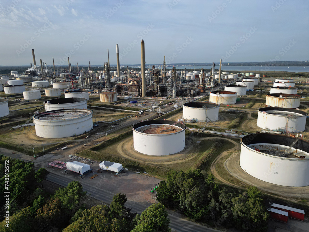 Aerial view of UK oil refinery and oil storage tanks in Fawley, Hampshire. White oli storage tanks and petrochemical complex with chimneys.