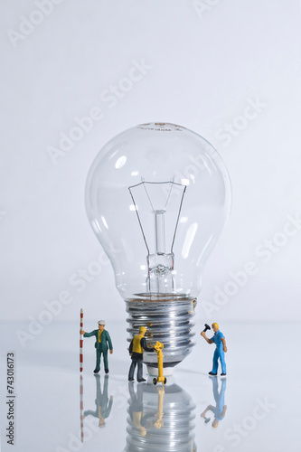 Photography of miniature people and toy figures, a group of workers standing next to a light bulb, concept: good ideas at work