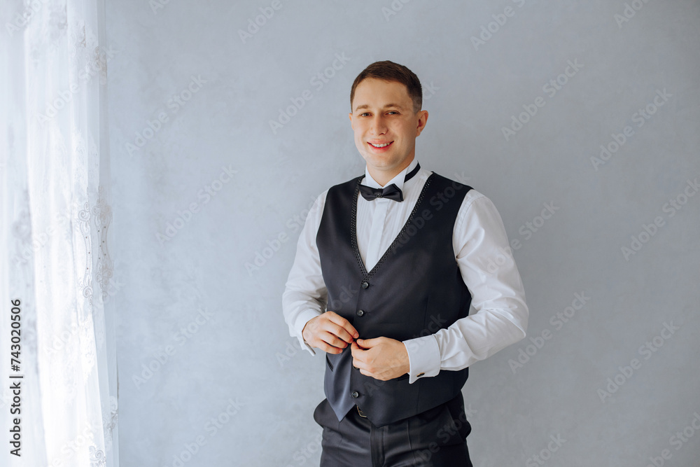 young smiling man buttoning his waistcoat in the morning before the wedding. close-up of a man in a business suit. Businessman puts on a suit. A man fastens the buttons on his jacket. young smiling man buttoning his waistcoat in the morning before the wedding. close-up of a man in a business suit. Businessman puts on a suit. A man fastens the buttons on his jacket.