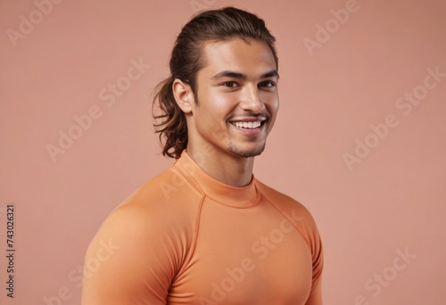 An athletic man in a form-fitting orange top, his stance showing off a fit and healthy physique.