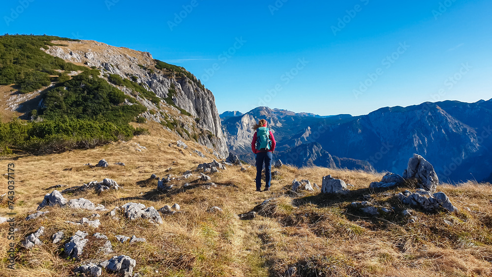 Hiker woman on idyllic hiking trail to mountain peak Hochblaser in Eisenerz, Ennstal Alps, Styria, Austria. Panoramic view of majestic alpine landscape in remote nature in summer. Wanderlust concept